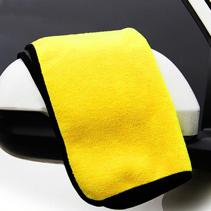 Yellow microfiber towel draped over a car mirror with a black border.