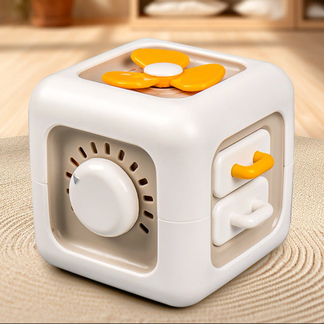 White and orange cube-shaped toy with a fan on a textured surface