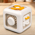 White and orange cube-shaped toy with a fan on a textured surface