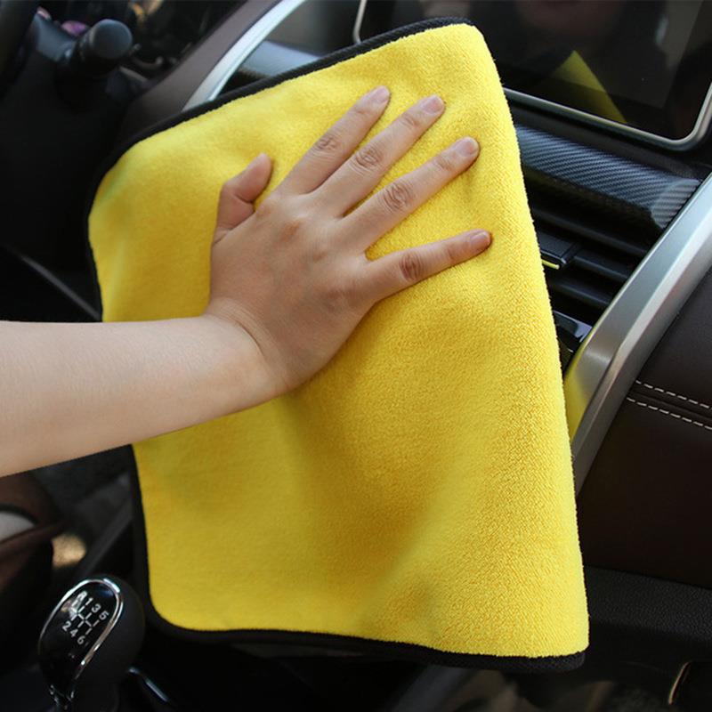 Person cleaning car interior with a yellow microfiber towel
